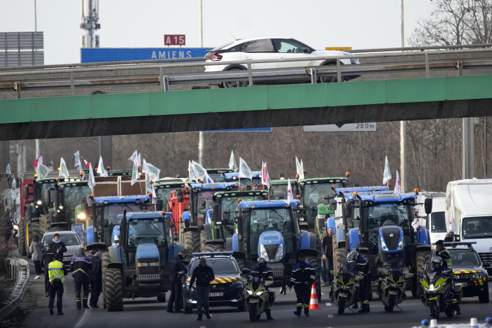 Police forces monitor a farmers demonstration on a highway, Monday, Jan. 29, 2024 in Argenteuil, north of Paris. Protesting farmers were encircling Paris with tractor barricades and drive-slows on Monday, using their lumbering vehicles to block highways leading to France's capital to pressure the government over the future of their industry, which has been shaken by repercussions of the Ukraine war. (AP Photo/Christophe Ena)