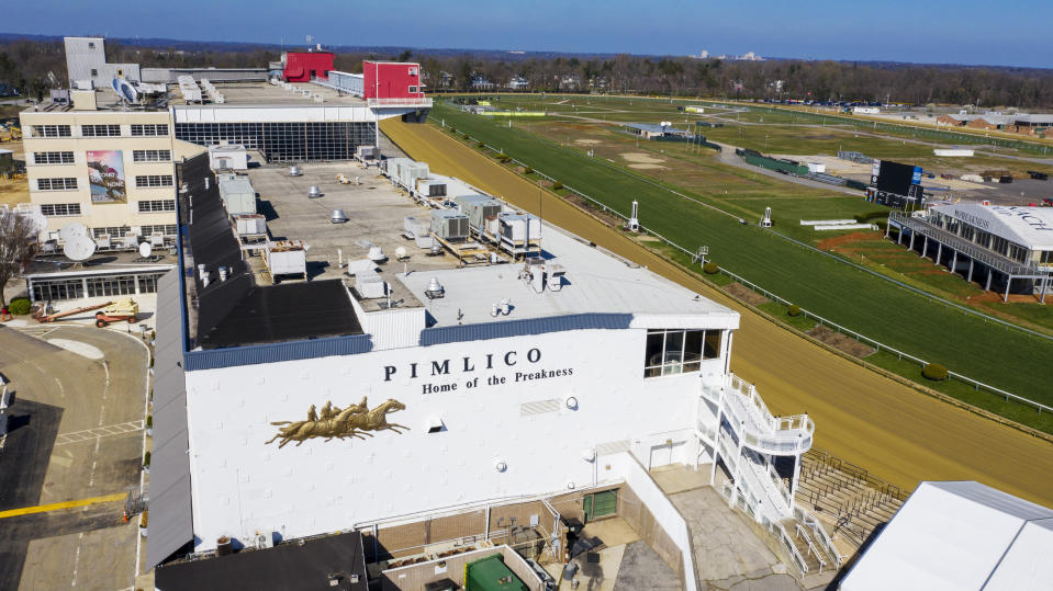 FILE - In this March 26, 2020, file photo, tractors groom the racing surface at the Pimlico Race Track in Baltimore, Md. The Preakness will remain at Pimlico Race Course into the foreseeable future, thanks to the passing of a bill to redevelop Maryland's race tracks with $375 million in bonds. (AP Photo/Steve Helber, File)