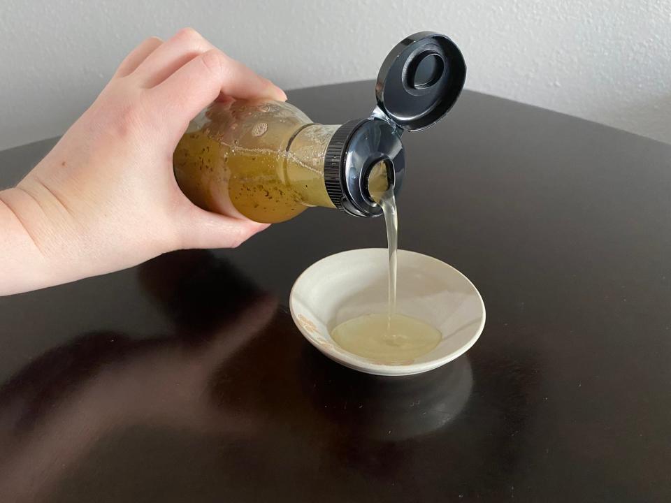 The writer pours the Specially Selected house vinaigrette into a small bowl