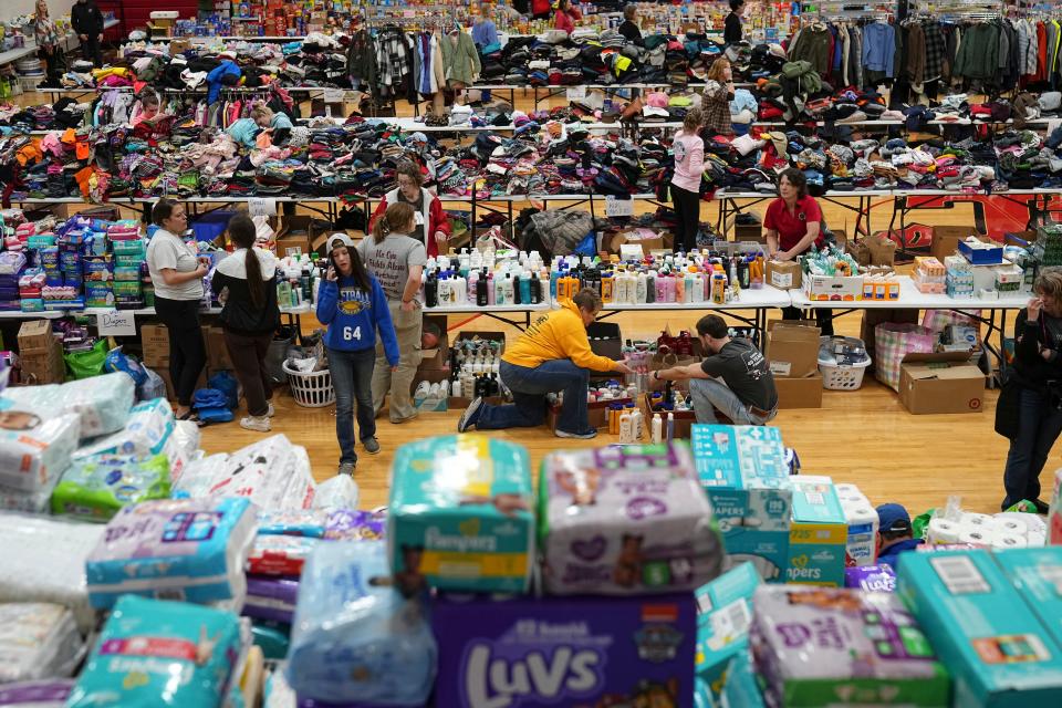 Volunteers sort through donations inside the Indian Lake High School gym on Friday, March 15, 2024, after a tornado struck the area the night before, killing three people and injuring some 20 others.