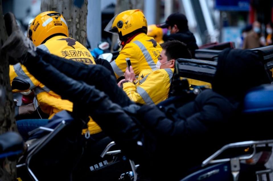 Motociclistas que hacen despachos a domicilio esperan a que les lleguen los pedidos en una calle en Shanghái