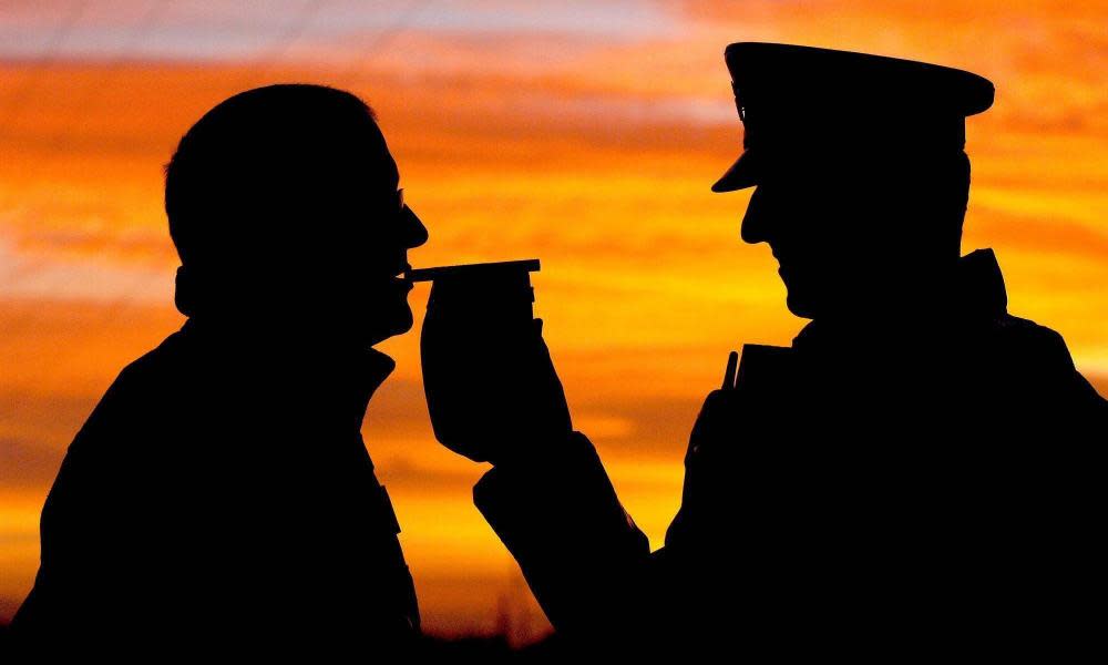 A police officer gives a motorist a breath test