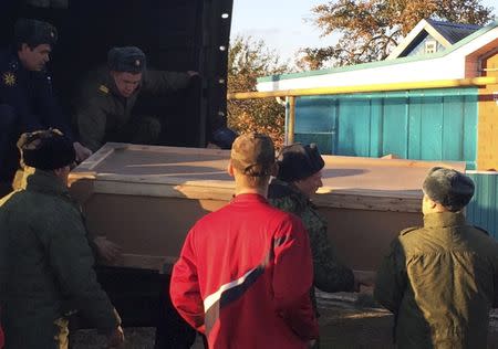 Russian servicemen unload a coffin containing the body of Vadim Kostenko, one of the Russian air force's support staff in Syria, from a truck near his family's house in the village of Grechnaya Balka, north-west of Krasnodar, Russia, October 27, 2015. The body of the first Russian serviceman confirmed dead in four weeks of air strikes in Syria was delivered on Tuesday to his parents, who said they were not convinced by the military's account that their 19-year-old son had hanged himself. In an interview with Reuters at their home in southern Russia before they received the body of their son Vadim, Alexander and Svetlana Kostenko said their son had sounded cheerful over the phone as recently as Saturday, the day he died while working at an air base on the Syrian coast. REUTERS/Maria Tsvetkova