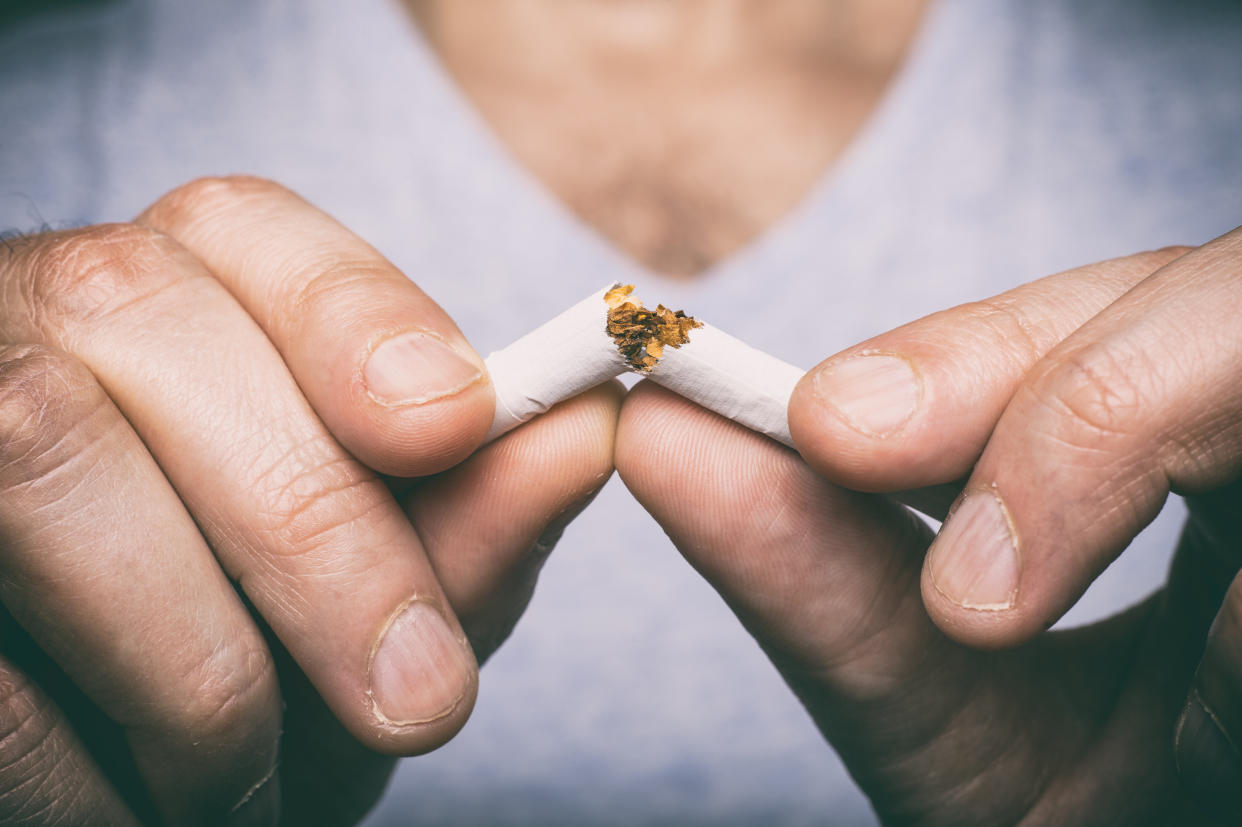 A man breaks a cigarette in half.