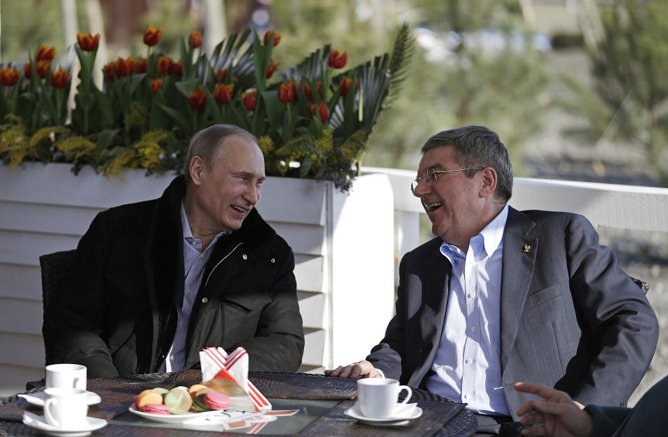 Russian President Vladimir Putin, left, and International Olympic Committee President Thomas Bach sit at a cafe along the promenade on the Black Sea near the Olympic Park at the 2014 Winter Olympics, Saturday, Feb. 15, 2014, in Sochi, Russia. (AP Photo/David Goldman)