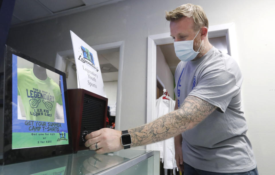 Wes Melton adjusts an ozone air filter that helps sanitize his martial arts daycare summer camp in Richardson, Texas, Tuesday, May 19, 2020. As daycare and youth camps re-open in Texas, operators are following appropriate safety measure to insure kids stay safe from COVID-19. (AP Photo/LM Otero)