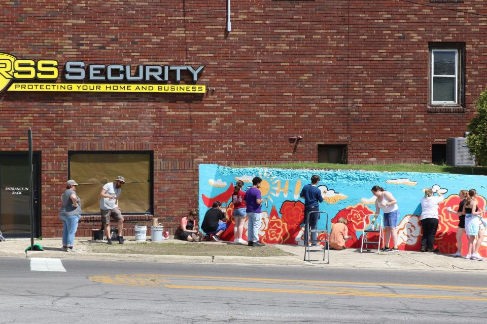 Members of the Ross Art Club work on an Ohio-themed mural, near the fairgrounds.