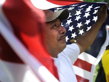 Amilcar Ramirez weeps as he holds a U.S. flag at a May Day rally in Lafayette Square Park near the White House in Washington, May 1, 2010. REUTERS/Jonathan Ernst