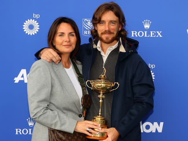 <p>Andrew Redington/Getty</p> Tommy Fleetwood and wife Clare Fleetwood pose with the Ryder Cup Trophy in September 2021.