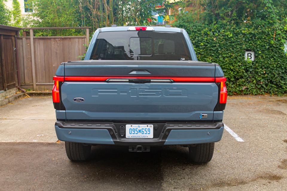 A blue 2023 Ford F-150 Lightning Platinum, viewed from the rear.