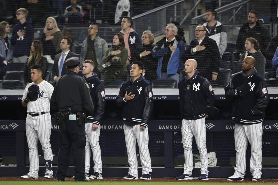 New York Yankees players listen to "God Bless America" during the seventh-inning stretch of the team's baseball game against the Kansas City Royals, Thursday, April 18, 2019, in New York. The Yankees have suspended the use of Kate Smith's recording of the song while they investigate an allegation of racism against the singer. The New York Daily News reported there are conflicting claims about Smith's 1939 song "That's Why Darkies Were Born." The song originated in the 1931 Broadway review "George White's Scandals," and was considered satire. It was recorded by Smith and by Paul Robeson, who was black. (AP Photo/Julio Cortez)