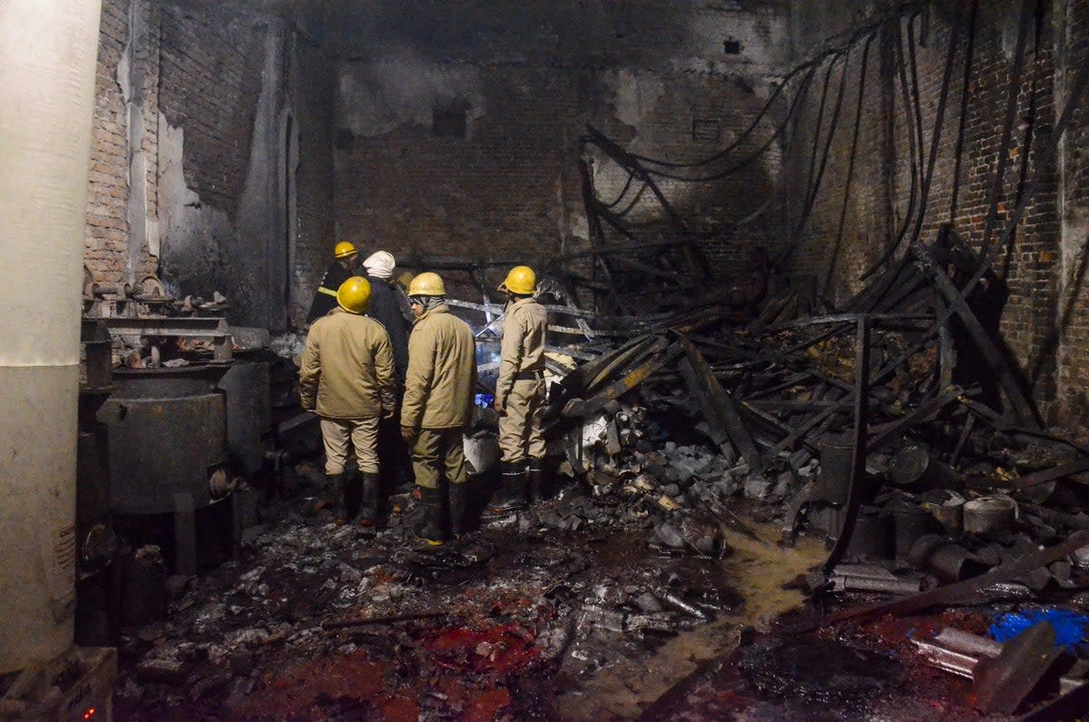 Fire brigade personnel look on after dousing a late Thursday fire at a paint factory in the Alipur area in northern New Delhi, India, Friday, 16 February 2024 (AP)