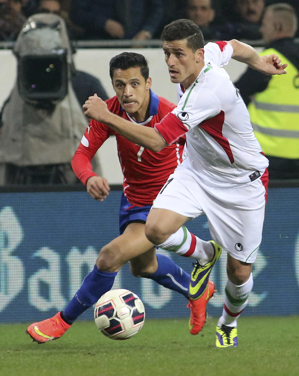 FILE — Voria Ghafouri, right, then an Iranian national team soccer player, challenges for a ball with Chile's Alexis Alejandro Sanchez during a friendly soccer match in St. Poelten, Austria, March 26, 2015. The semiofficial Fars and Tasnim news agencies reported on Thursday, Nov. 24, 2022, that Iran arrested Ghafouri, a prominent former member of its national soccer team for insulting the national soccer team, which is currently playing in the World Cup, and criticizing the government as authorities grapple with nationwide protests. (AP Photo/Ronald Zak, File)