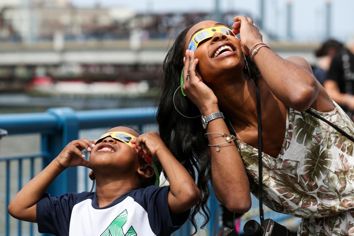 <span>A mother and son watch the eclipse in Boston on 21 August 2017.</span><span>Photograph: Angela Rowlings/Boston Herald via Getty Images</span>