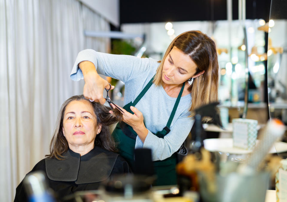 a hair stylist cuts a customer's hair