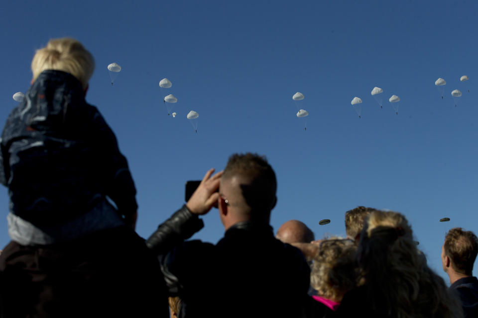 Spectators watch a mass parachute drop at Ginkel Heath, eastern Netherlands, Saturday, Sept. 21, 2019, as part of commemorations marking the 75th anniversary of Operation Market Garden, an ultimately unsuccessful airborne and land offensive that Allied leaders hoped would bring a swift end to World War II by capturing key Dutch bridges and opening a path to Berlin. (AP Photo/Peter Dejong)