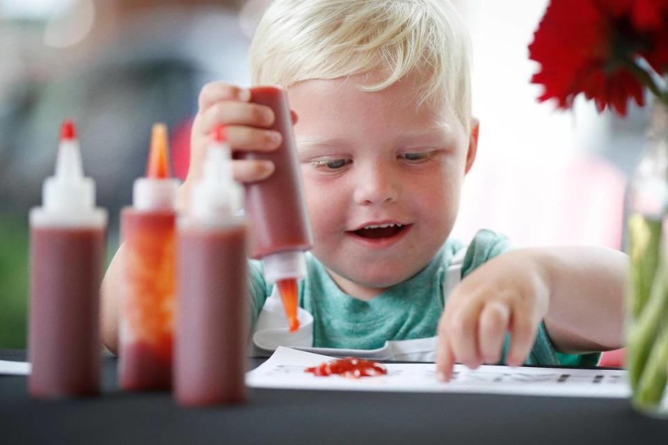 Asher Lawson, 3, of Owensboro, Ky., reacts while finger painting with ketchup during Ketchup Art on the Green at The Summit at Fritz Farm in Lexington, Saturday, July 31, 2021.