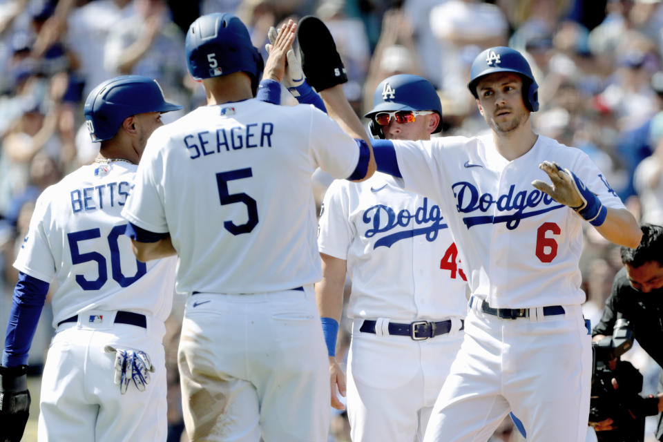 Los Angeles Dodgers' Trea Turner, right, gets congratulations from Corey Seager (5), Mookie Betts (50), and Matt Beaty (45), after Turner hit a grand slam home run against the Milwaukee Brewers during the fifth inning of a baseball game in Los Angeles, Sunday, Oct. 3, 2021. (AP Photo/Alex Gallardo)