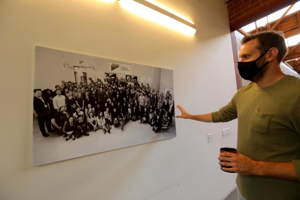 A man looks at a photograph on a wall.