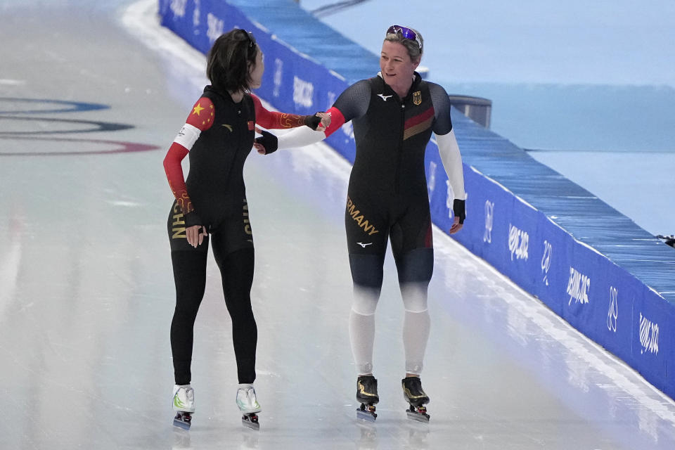 Ahenaer Adake of China, left, and Claudia Pechstein of Germany, greet each other after competing in their heat of the women's speedskating 3,000-meter race at the 2022 Winter Olympics, Saturday, Feb. 5, 2022, in Beijing. (AP Photo/Sue Ogrocki)