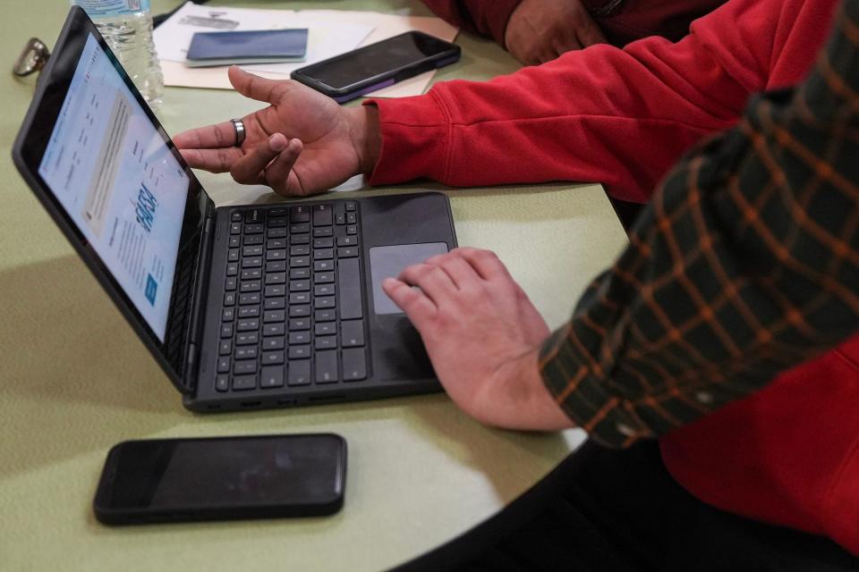 Joe Castillo with the Austin school district helps a student fill out information for the FAFSA at Travis Early College High School on Feb. 7.