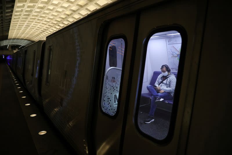 A passenger wearing a protective face mask uses a cell phone, following the WMATA Metro rule stating riders must wear protective face masks amid the coronavirus disease (COVID-19) outbreak, in Washington