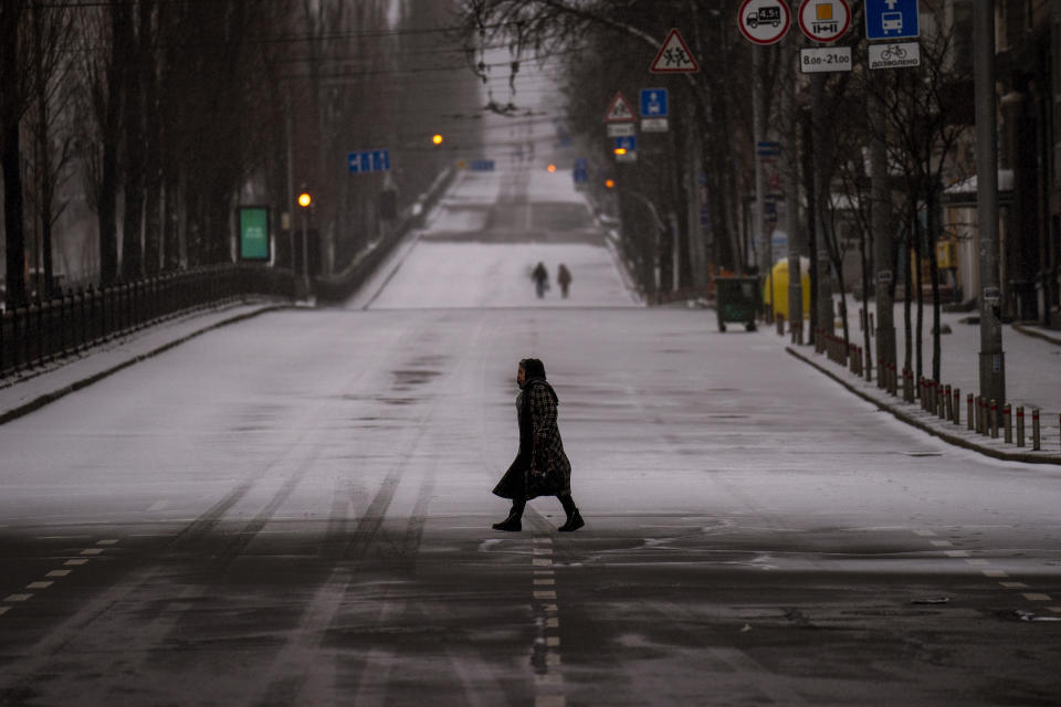People walk along an empty road during curfew, in Kyiv, Ukraine, Tuesday, March 1, 2022. Explosions and gunfire that have disrupted life since the invasion began last week appeared to subside around Kyiv overnight, as Ukrainian and Russian delegations met Monday on Ukraine's border with Belarus. (AP Photo/Emilio Morenatti)
