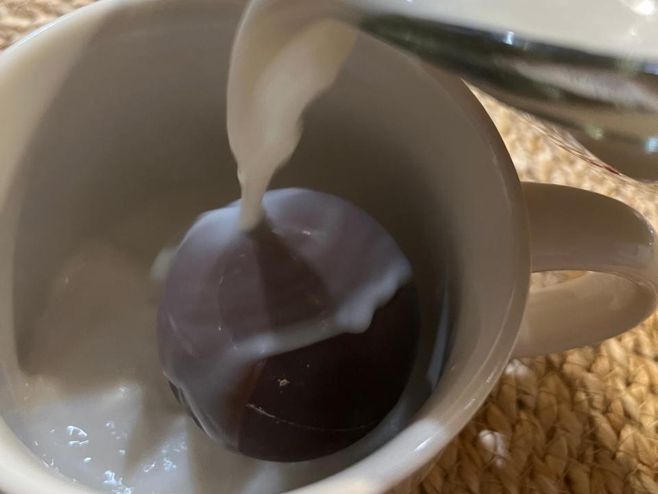 Hot-cocoa bomb in mug with milk being poured over it
