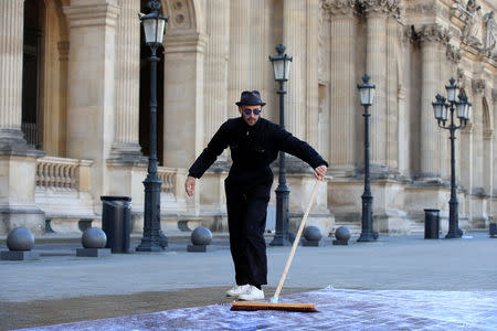 French artist JR works in the courtyard of the Louvre Museum near the glass pyramid designed by Leoh Ming Pei as the Louvre Museum celebrates the 30th anniversary of its glass pyramid in Paris, France, March 26, 2019. REUTERS/GonzaloÊFuentes