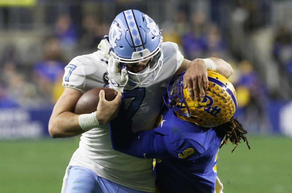 North Carolina quarterback Sam Howell, left, fights for yards as Pittsburgh defensive back Brandon Hill delivers a hit at Heinz Field.