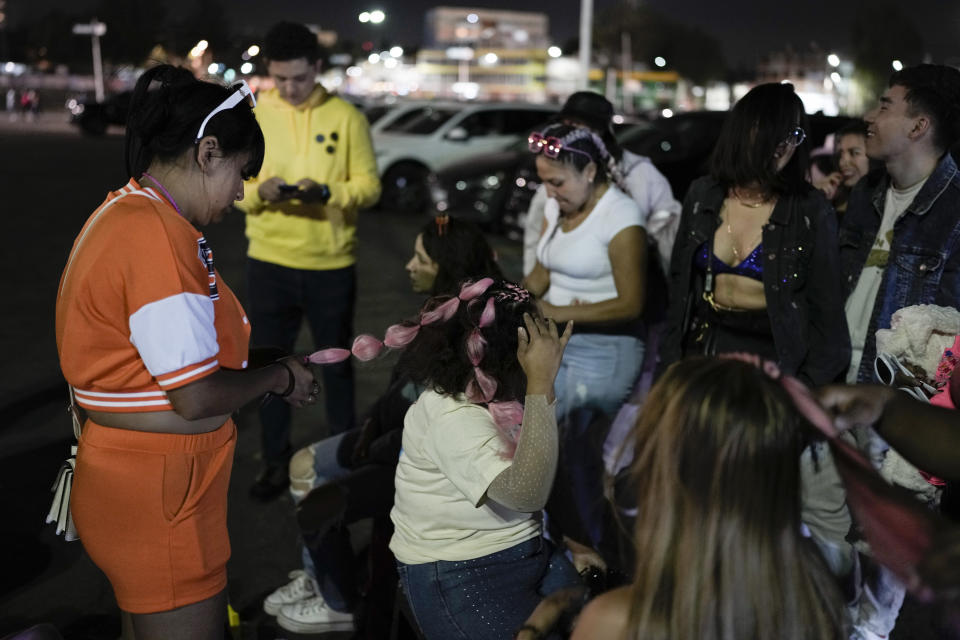 Una mujer se coloca extensiones de cabello rosadas previo al concierto de la gira "Mañana será bonito" de Karol G en el Estadio Azteca de la Ciudad de México el jueves 8 de febrero de 2024. (Foto AP/Eduardo Verdugo)