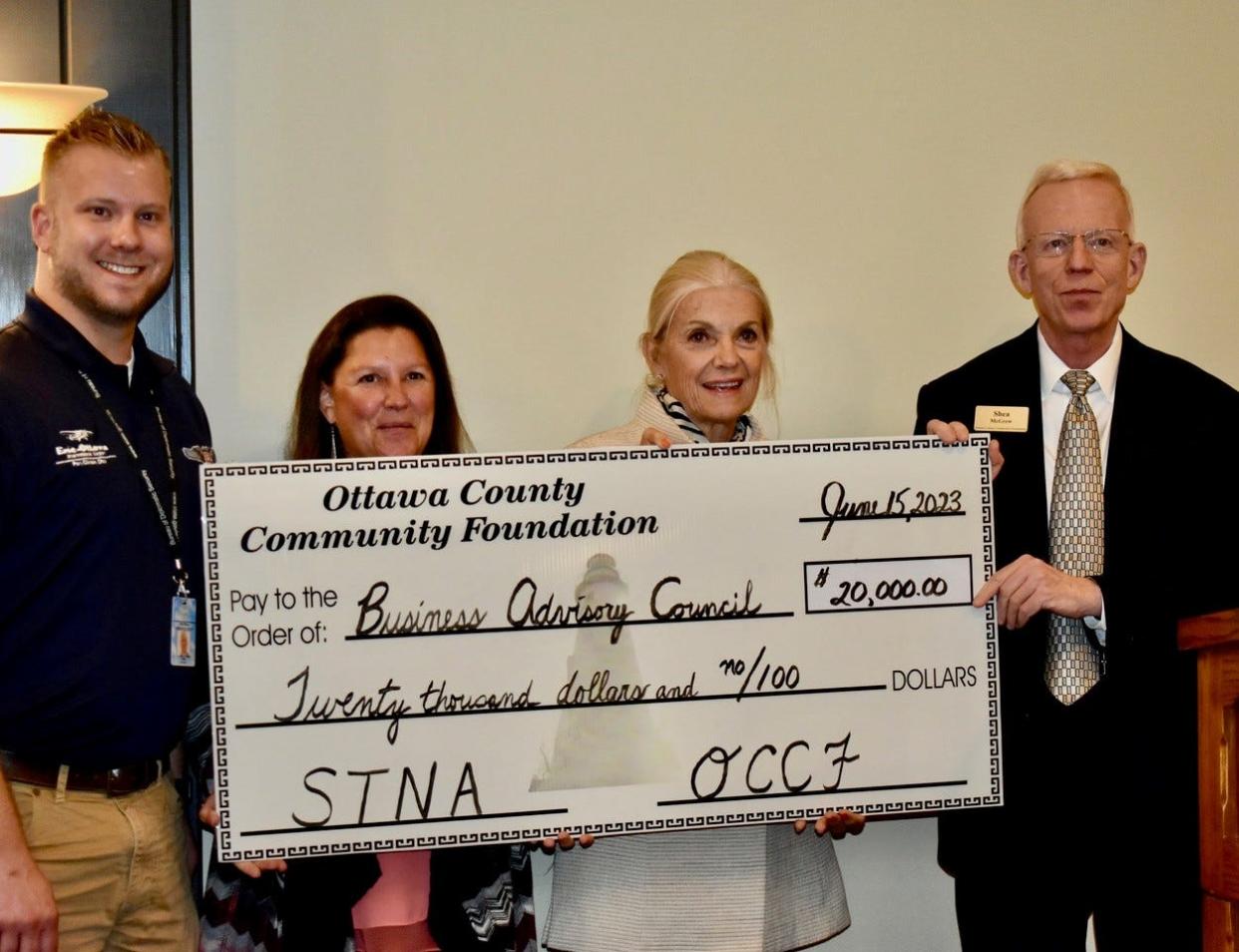 Business Advisory County representatives Clay Finken, left, and Katherine Adams accept a check for $20,000 from Ottawa County Community Foundation (OCCF) Trustee Mary Coffee and Executive Director Shea McGrew.