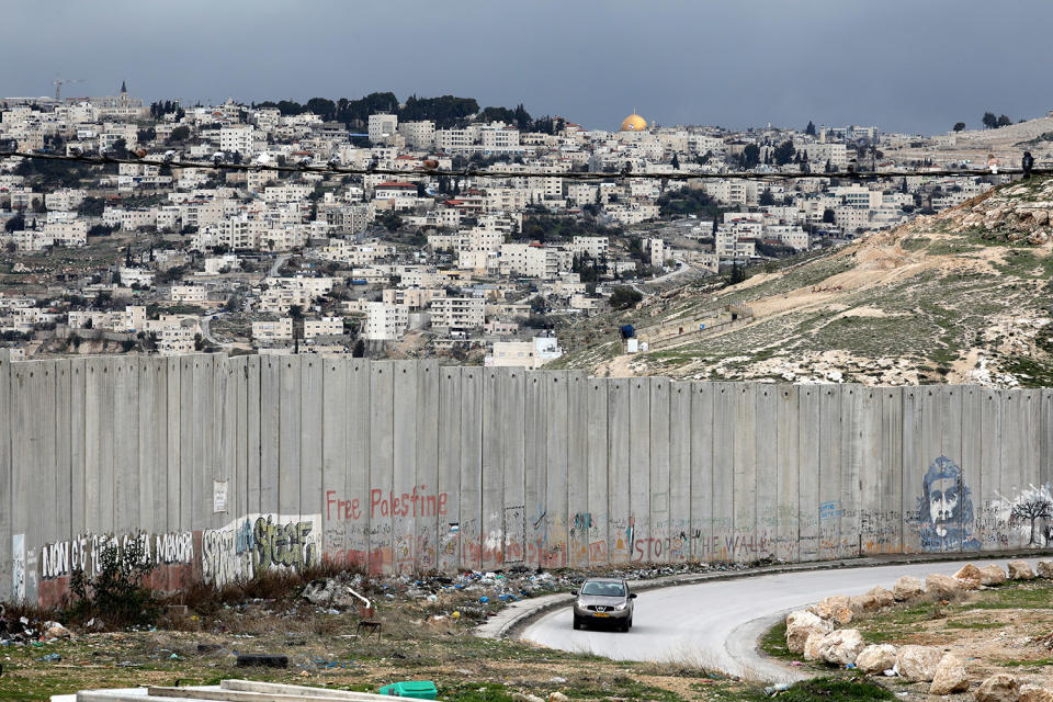 A car drives along a road near the Israeli barrier in the West Bank