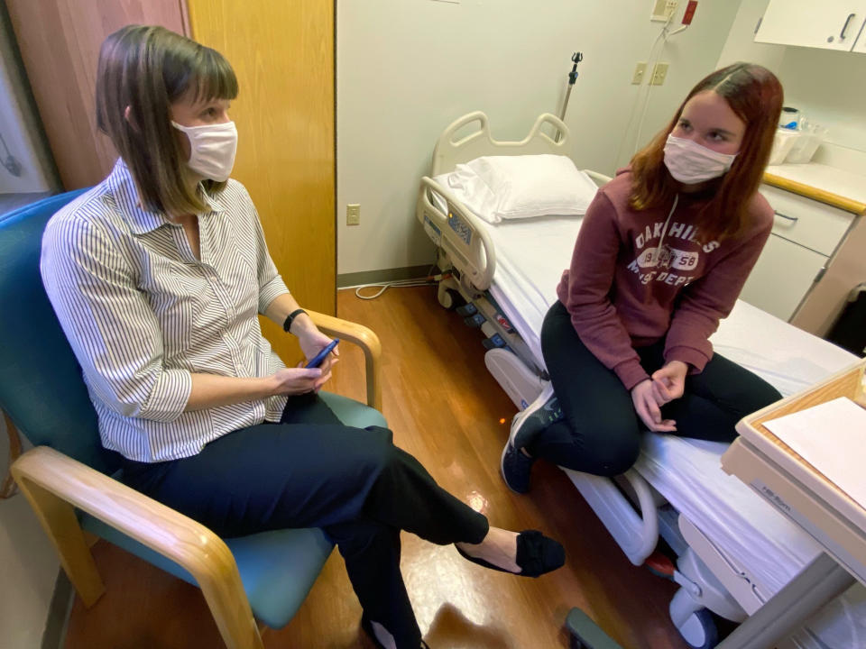 In this photo provided by Cincinnati Children’s Hospital Medical Center, Katelyn Evans, right, a trial participant, speaks to her mother Laurie Evans ahead of receiving an injection in Pfizer's COVID-19 vaccine trial at Cincinnati Children’s Hospital Medical Center on Wednesday, Oct. 14, 2020. (Cincinnati Children’s Hospital Medical Center via)