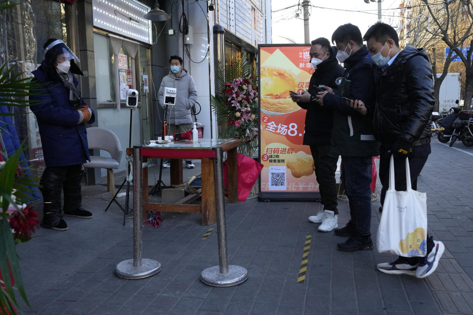 Residents show their health code before they enter a market with some shops re-opening for business as restrictions are eased in Beijing, Saturday, Dec. 3, 2022. Chinese authorities on Saturday announced a further easing of COVID-19 curbs with major cities such as Shenzhen and Beijing no longer requiring negative tests to take public transport. (AP Photo/Ng Han Guan)