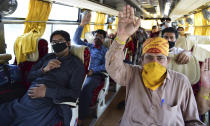 Pakistani nationals stranded in India wave sitting in a bus that will take them to the border, at the Integrated Check Post (ICP) at the India-Pakistan Wagah-Attari border, about 35 kilometers from Amritsar, India, Tuesday, May 5, 2020. Nearly 200 Pakistanis stranded in a nationwide coronavirus lockdown on the other side of the border in India have been able to cross back home. Border security forces allowed on Tuesday masked passengers in private vehicles with luggage strapped to the roof to cross the Attari-Wagah border that separates the sprawling Punjab region split between Indian and Pakistan. The border opened on Tuesday for the first time since the ongoing lockdown began. (AP Photo/Prabhjot Gill)