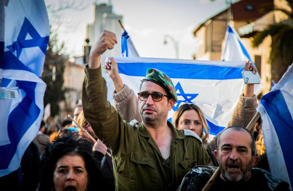 An Israeli reserve soldier raises his fist as he marches during a demonstration on Feb. 13, 2023, in Jerusalem to protest proposed judicial reform. <a href="https://www.gettyimages.com/detail/news-photo/an-israeli-reserve-soldier-raises-his-fist-as-he-marches-news-photo/1247124493?phrase=israel%20protest&adppopup=true" rel="nofollow noopener" target="_blank" data-ylk="slk:Eyal Warshavsky/SOPA Images/LightRocket via Getty Images;elm:context_link;itc:0;sec:content-canvas" class="link ">Eyal Warshavsky/SOPA Images/LightRocket via Getty Images</a>