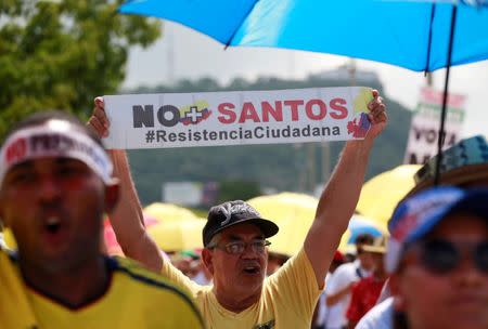 A demonstrator holds a sign reading "No more (President Juan Manuel) Santos, #citizen resistance" during a protest against the government's peace accord with the Revolutionary Armed Forces of Colombia (FARC), which would allow rebels to enter parliament without serving any jail time, in Cartagena, Colombia, September 26, 2016. REUTERS/John Vizcaino