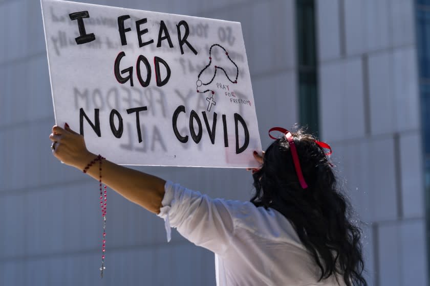 A protestor opposing COVID-19 vaccine mandates holds a sign in front of City Hall in Los Angeles Sept. 18, 2021.