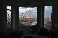The scene of the explosion that hit the seaport of Beirut is seen through a damaged apartment in Beirut, Lebanon, Monday, Aug. 10, 2020. World leaders and international organizations pledged nearly $300 million in emergency humanitarian aid to Beirut in the wake of the devastating explosion, but warned on Sunday that no money for rebuilding the capital will be made available until Lebanese authorities commit themselves to the political and economic reforms demanded by the people. (AP Photo/Bilal Hussein)