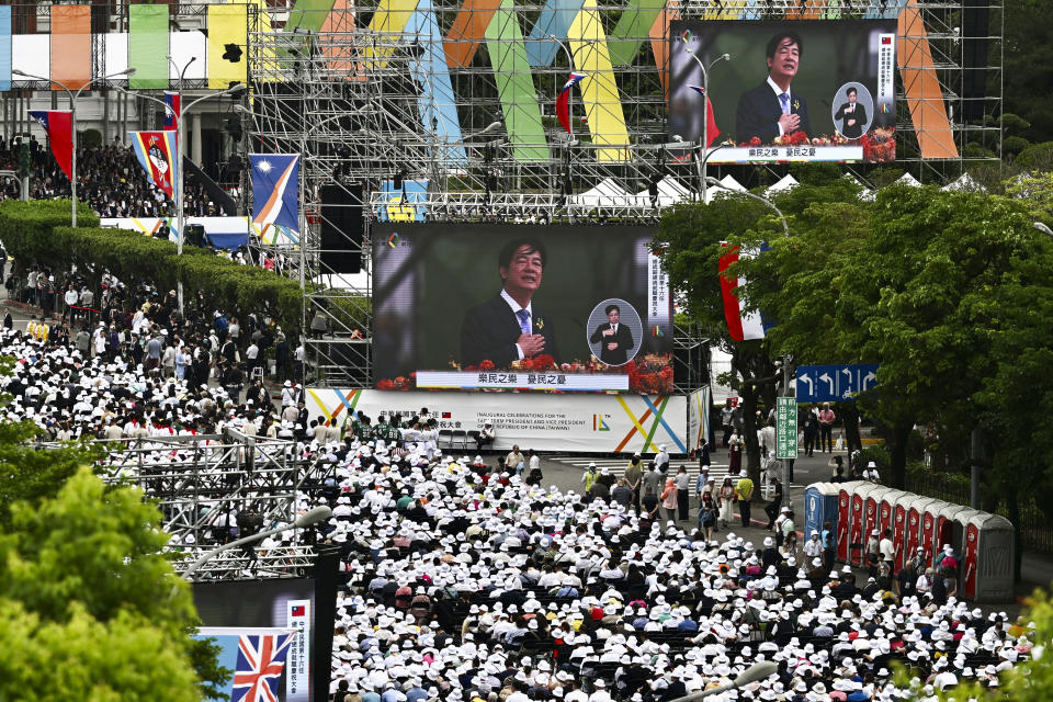 In this photo released by the Taipei News Photographer, people gather to watch monitor screens showing new President Lai Ching-te delivering a speech during Lai's inauguration ceremonies in Taipei, Taiwan, Monday, May 20, 2024. Lai was sworn in as Taiwan's new president Monday, beginning a term in which he is expected to continue the self-governing island's policy of de facto independence from China while seeking to bolster its defenses against Beijing. (Taipei News Photographer via AP)