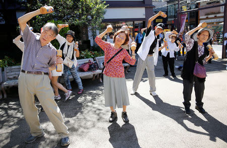 Elderly and middle-aged people exercise with wooden dumbbells during a health promotion event to mark Japan's "Respect for the Aged Day" at a temple in Tokyo's Sugamo district, an area popular among the Japanese elderly, Japan, September 18, 2017. REUTERS/Toru Hanai