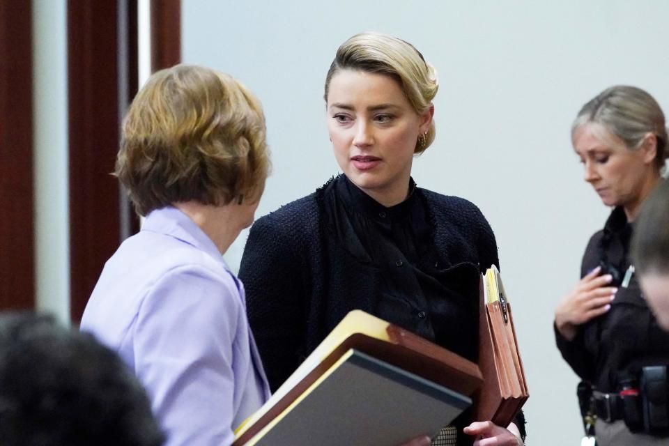Amber Heard talks to attorneys as lunch break starts, in the courtroom at the Fairfax County Circuit Courthouse in Fairfax, Virginia, on April 25, 2022.