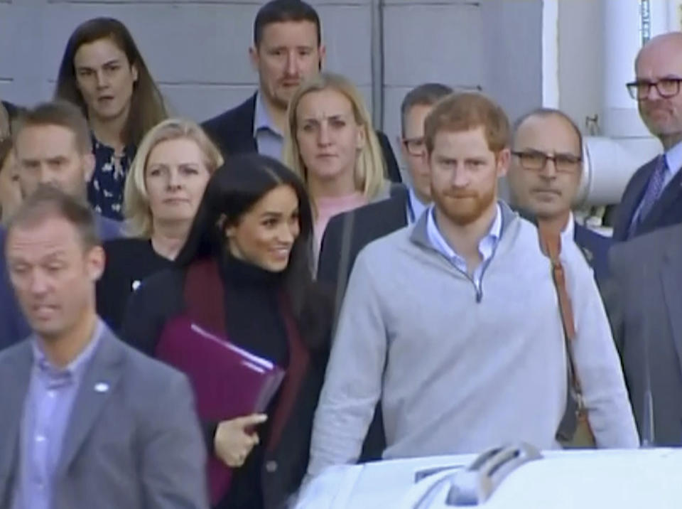 In this image made from video, Britain's Prince Harry, center right, and his wife Meghan, center left, Duke and Duchess of Sussex, approach a car at an airport in Sydney, Monday, Oct. 15, 2018. Prince Harry and his wife Meghan arrived in Sydney on Monday, a day before they officially start a 16-day tour of Australia and the South Pacific. Kensington Palace says Prince Harry and Meghan the Duchess of Sussex are expecting a child in the spring. (Australian Pool via AP)