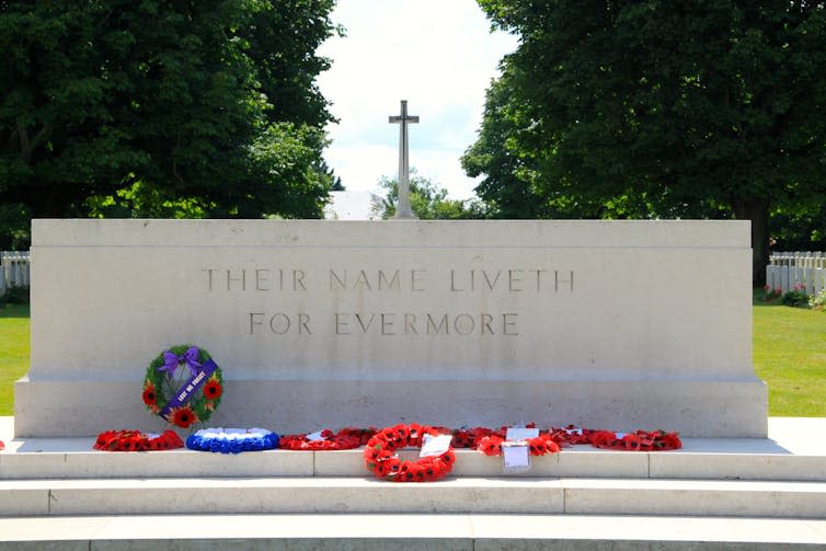 Wreaths laid against a war memorial plaque.