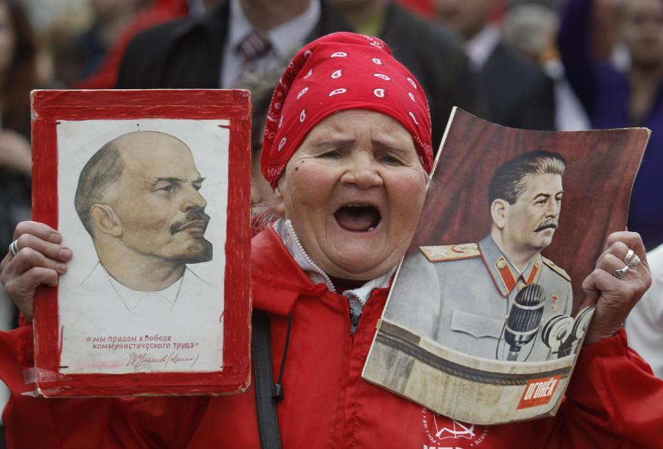 A woman shouts as she carries portraits of Soviet founder Vladimir Lenin, left, and Soviet dictator Josef Stalin, right, during a Communist Party supporters rally to mark May Day in Moscow, Russia, Tuesday, May 1, 2012. (AP Photo/Mikhail Metzel)