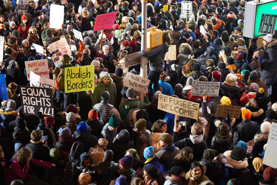 <p>Protestors gather at New York City's JFK International Airport on Jan. 28, 2017, in support of newly banned refugees and visitors wishing to enter the country. </p> <p>On Jan. 27, 2017, <a href="https://people.com/tag/donald-trump" rel="nofollow noopener" target="_blank" data-ylk="slk:President Donald Trump;elm:context_link;itc:0;sec:content-canvas" class="link ">President Donald Trump</a> signed an executive order that t<a href="https://people.com/politics/donald-trumps-new-travel-ban-6-muslim-majority-nations/" rel="nofollow noopener" target="_blank" data-ylk="slk:emporarily banned any refugees from entering the U.S.;elm:context_link;itc:0;sec:content-canvas" class="link ">emporarily banned any refugees from entering the U.S.</a>, indefinitely banned refugees who hail from Syria and temporarily banned citizens from several Muslim countries from entering the U.S. The order also required a “religious test” of sorts for refugees attempting to enter the U.S., giving preferential treatment to Christian and other religious minorities who live in Muslim countries over Muslims. The order, called the “Muslim ban” by Trump’s critics, outraged many and caused bottlenecks at major U.S. airports as stranded travelers filed for emergency appeals. The ACLU and others have fought the order in court since it was first introduced, though in 2018, the Supreme Court upheld a third version of the ban signed by Trump.</p>