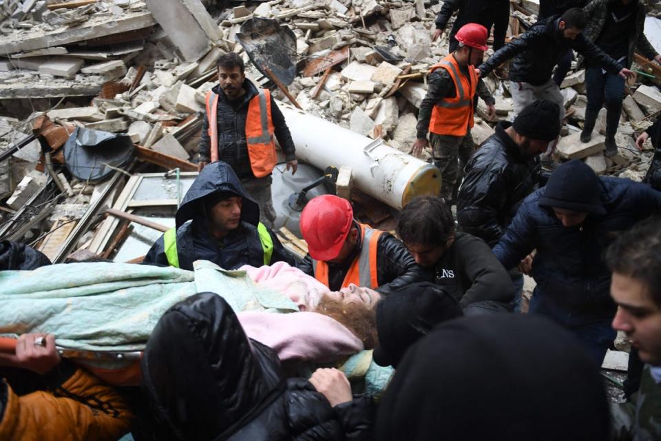 Members of the White Helmets carry an injured woman after rescuing her from the rubble of a collapsed building (AFP via Getty Images)