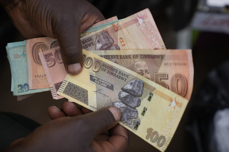 A currency trader holds worthless Zimbabwean dollar notes on the streets of Harare, Zimbabwe, Thursday, June, 9, 2022. Rampant inflation is making it increasingly difficult for people in Zimbabwe to make ends meet. Since the start of Russia’s war in Ukraine, official statistics show that Zimbabwe’s inflation rate has shot up from 66% to more than 130%. The country's finance minister says the impact of the Ukraine war is heaping problems on the already fragile economy. (AP Photo/Tsvangirayi Mukwazhi)