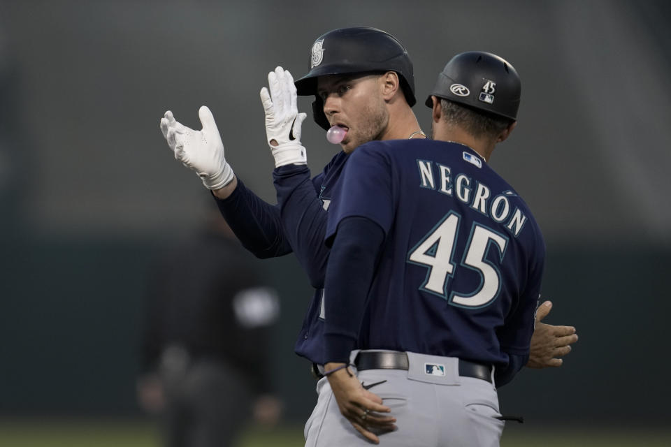 Seattle Mariners' Jarred Kelenic, left, celebrates next to first base coach Kristopher Negrón after hitting an RBI single against the Oakland Athletics during the second inning of a baseball game Tuesday, Sept. 19, 2023, in Oakland, Calif. (AP Photo/Godofredo A. Vásquez)